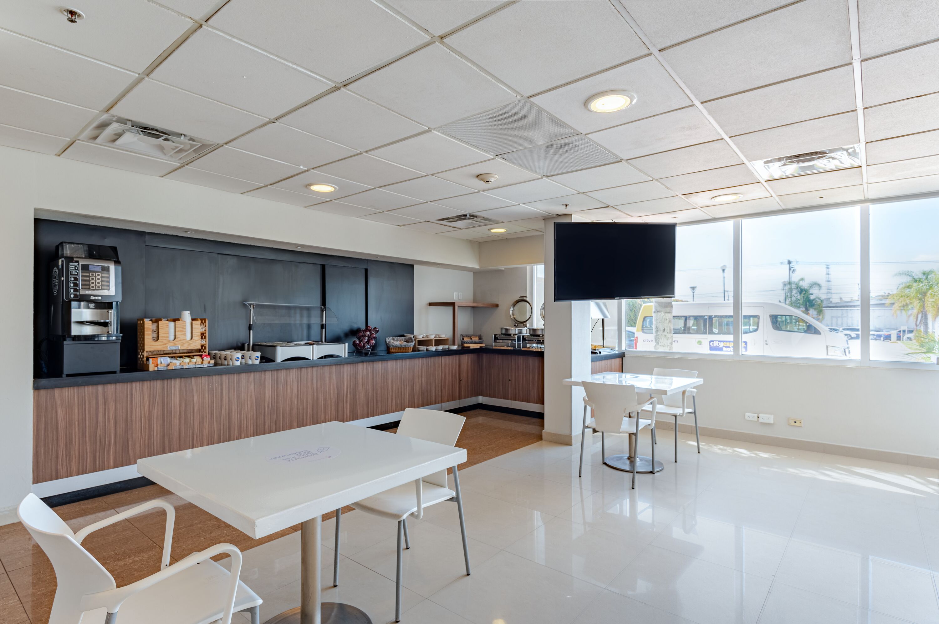 A modern cafe with a counter, seating area, and large windows.