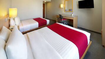 A hotel room with two beds, a desk, a chair, a TV, and a mirror.