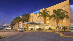 A hotel with a sign reading 'City Express by Marriott,' palm trees, and a van parked in front. - City Express by Marriott Tepotzotlan (Tepotzotlán)