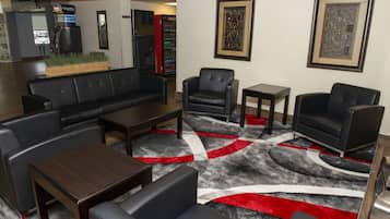 A lobby with a black leather sofa, armchairs, a coffee table, and a patterned rug.