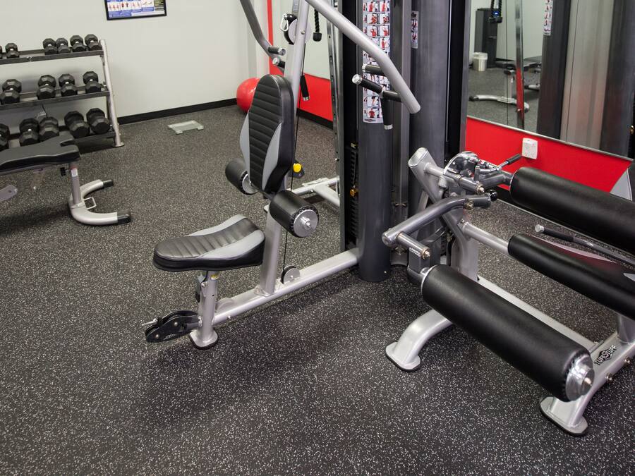 Une salle de sport équipée de matériel d’exercice, avec un miroir fixé au mur et une affiche accrochée au mur.