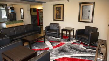 Una hall con un divano in pelle nera, due poltrone, un tavolino da caffè e un tappeto decorato.