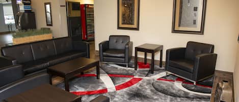 A lobby with a black leather sofa, two armchairs, a coffee table, and a patterned rug.