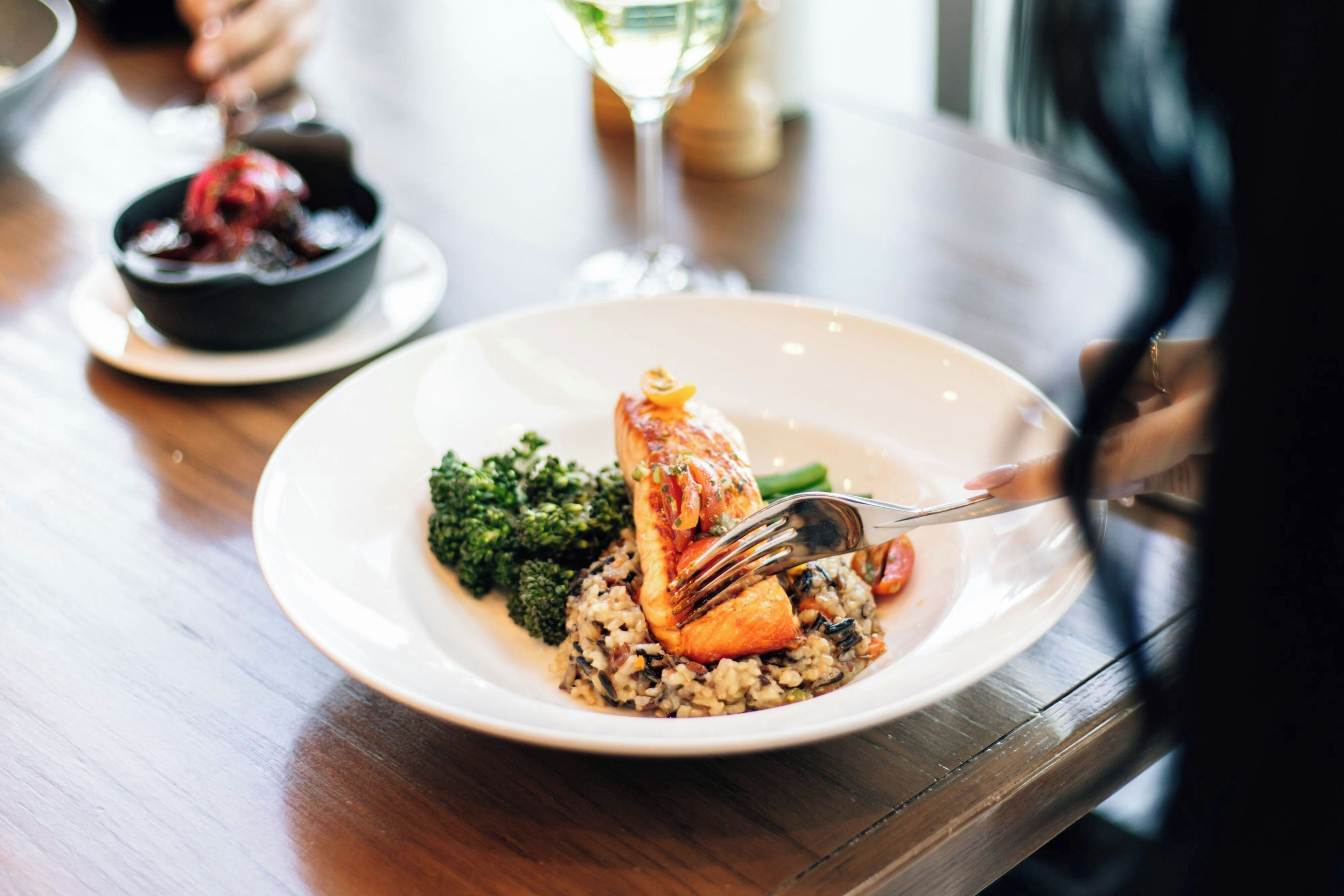 A plate of food with a fork on it, placed on a wooden table.