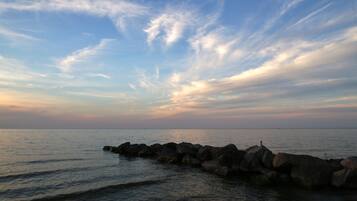 A coastal scene with a rocky breakwater and calm sea under a partly cloudy sky.