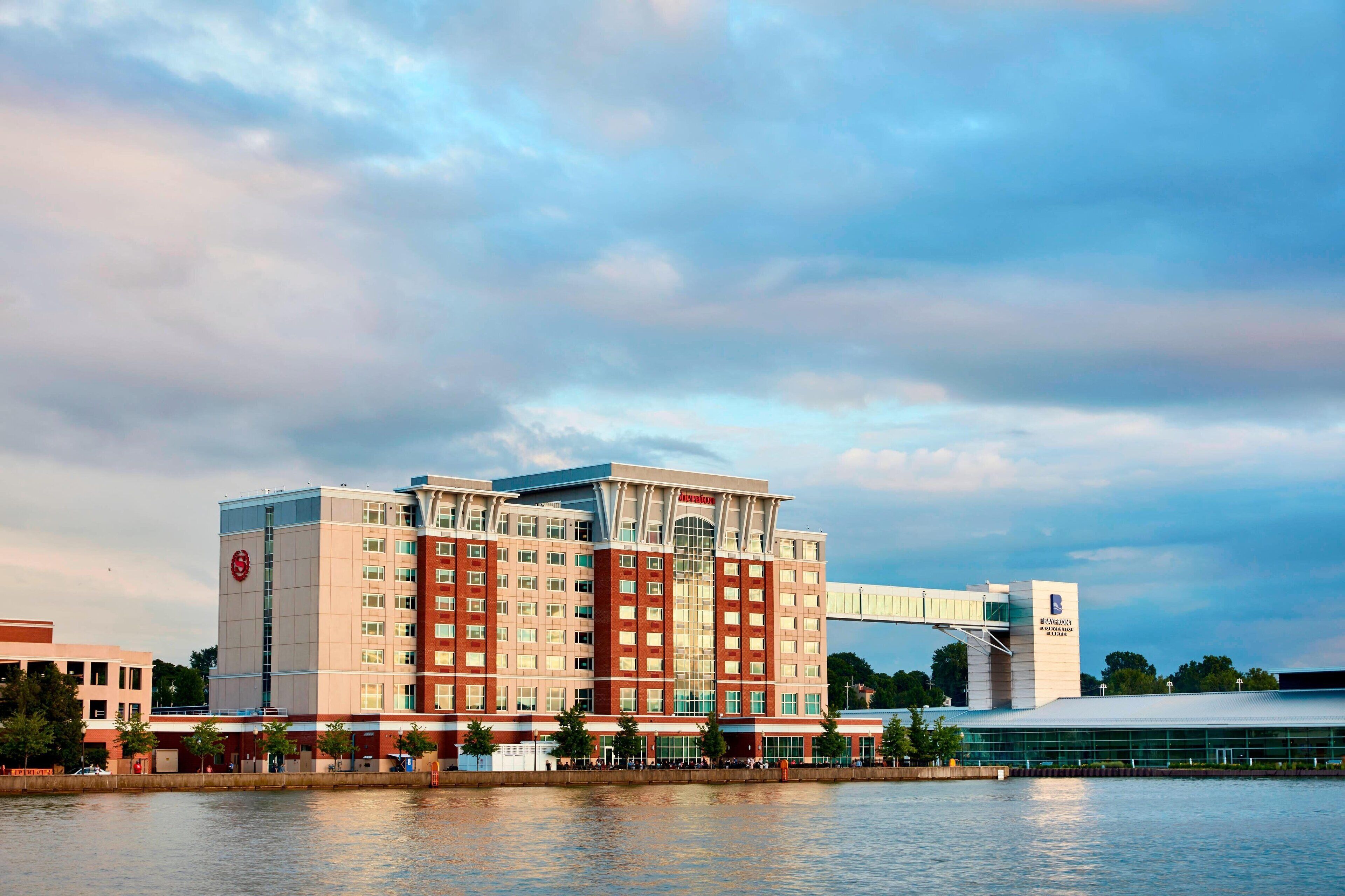 Een groot hotel met meerdere verdiepingen, een opvallende entree en uitzicht op het water.