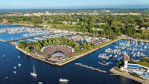 An aerial view of a marina with multiple docks and boats, surrounded by greenery and urban buildings. - Sheraton Erie Bayfront Hotel (Erie)