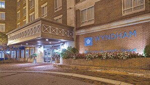 Entrada de un hotel con fachada de ladrillo, un área de acceso cubierta y un cartel que dice "WYNDHAM Old Town Alexandria Resort".