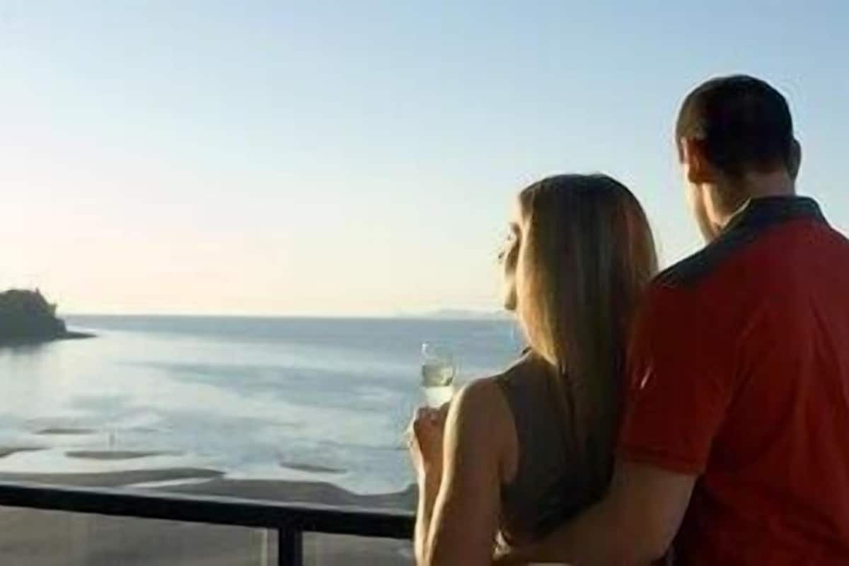 A couple overlooking a body of water from a balcony.