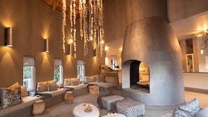 Un amplio salón con chimenea, asientos cómodos y una lámpara colgante original.