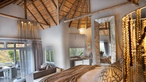 Un dormitorio espacioso con una cama grande, un balcón y un techo rústico.