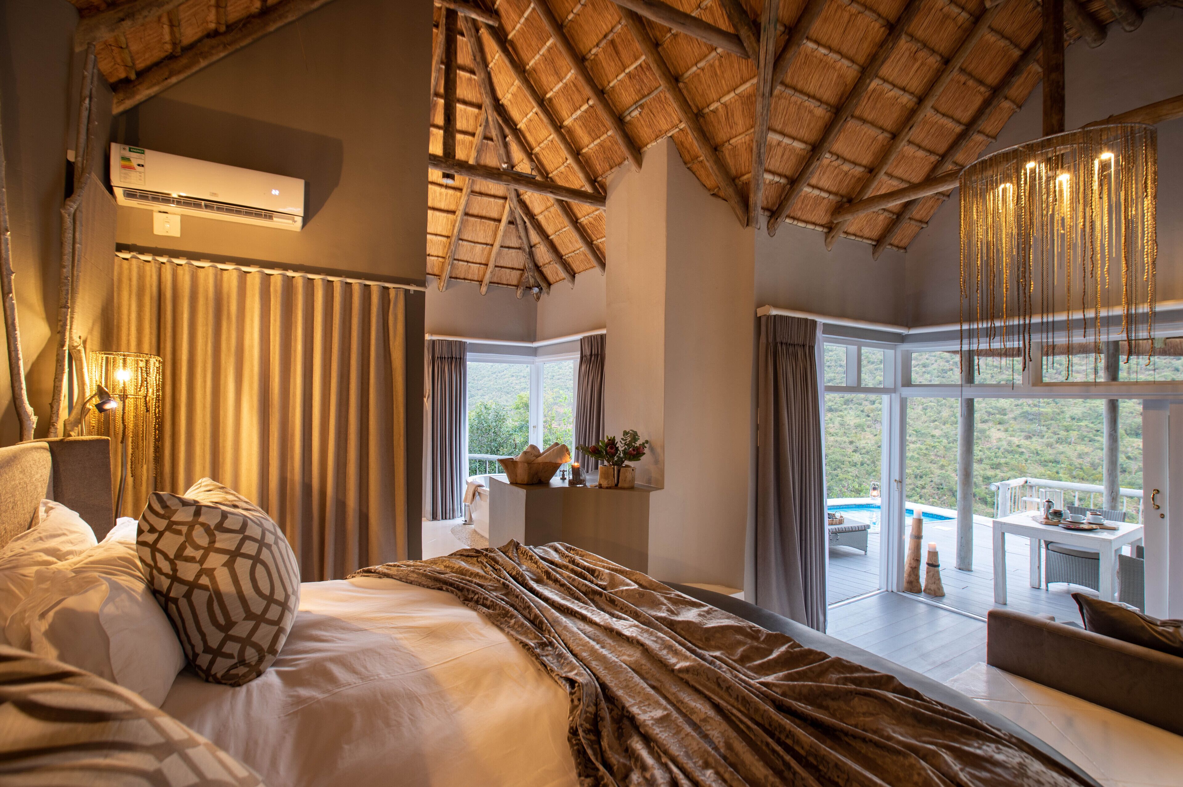A bedroom with a large bed, a view of a pool, and a dining area.
