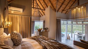 A bedroom with a large bed, a view of a pool, and a dining area.