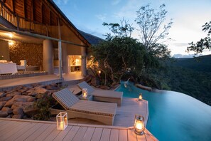 A poolside area with lounge chairs and a stone wall. - Clifftop Exclusive Safari Hideaway (Vaalwater)