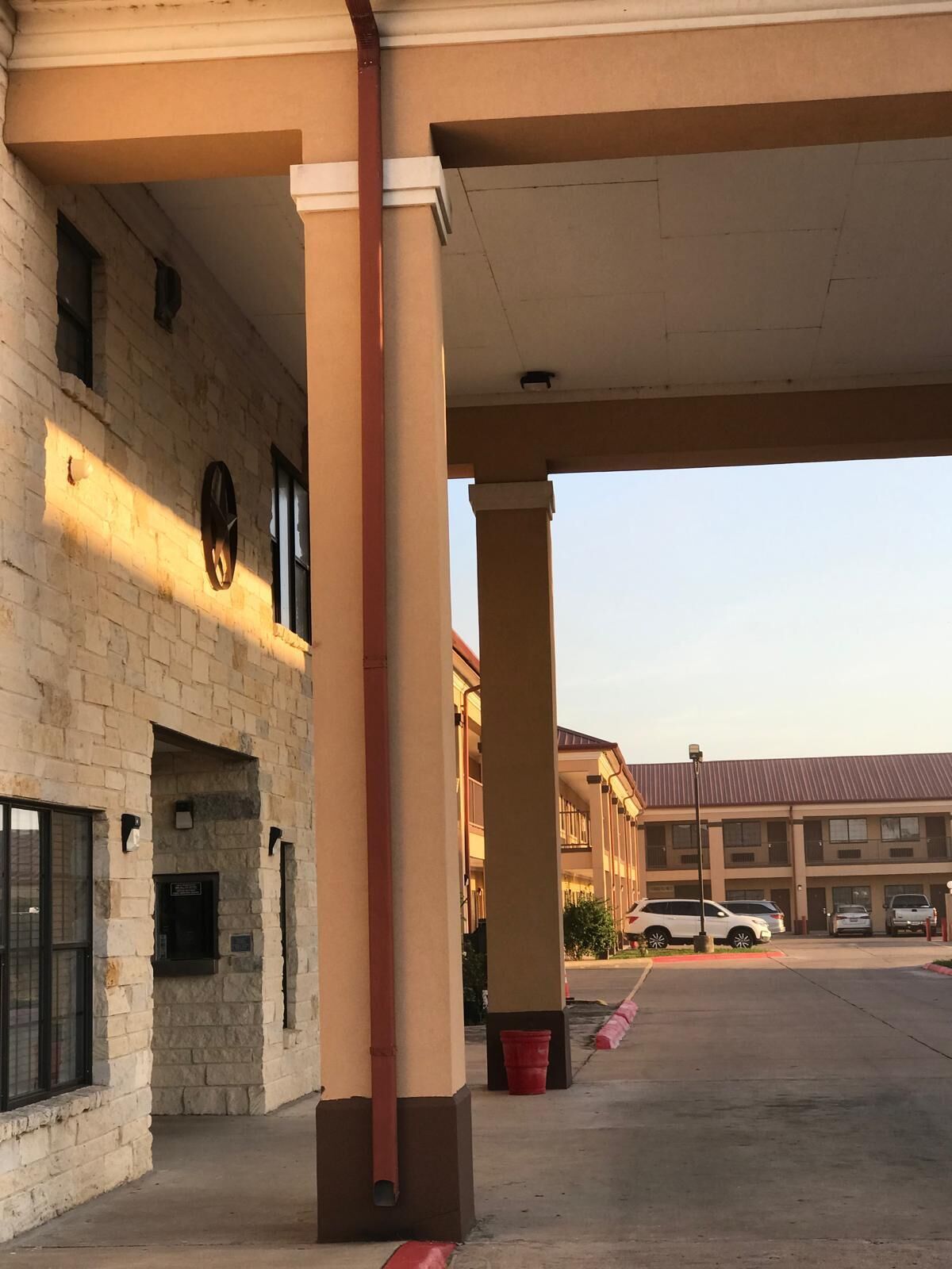 Un bâtiment à la façade en briques, doté d’un espace de stationnement couvert et surplombant un ciel dégagé.