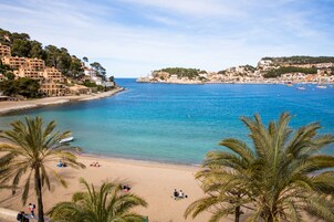 A coastal town with a sandy beach, palm trees, and a clear blue sea.