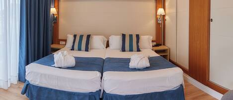 A hotel room with a large bed, two bedside tables, a wooden headboard, and a wardrobe.