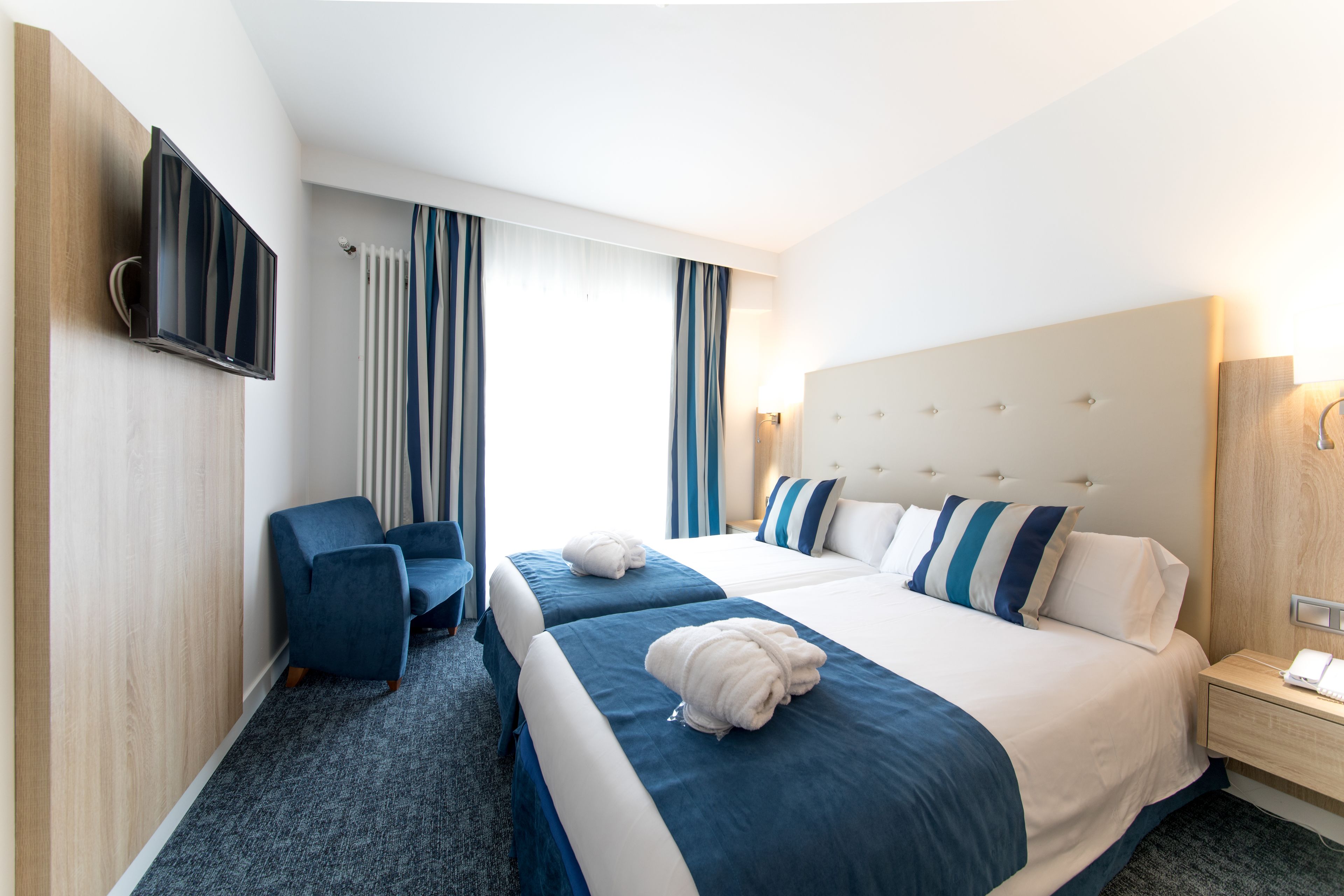 A hotel room with two beds, a TV, a desk, and a chair.