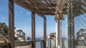 En træpergola med udsigt til havet og bygninger i baggrunden.