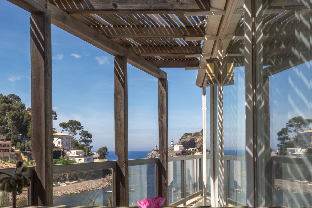 A wooden pergola with a view of the sea and buildings in the background.