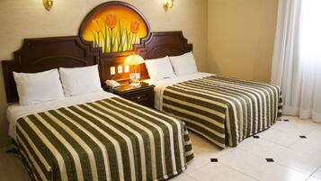 Habitación de hotel con dos camas, una mesita de noche, una lámpara y un cuadro en la pared.
