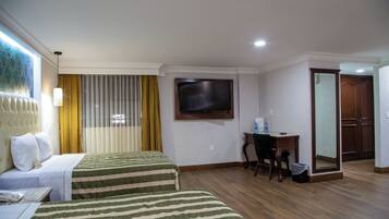 A hotel room with two beds, a desk with a chair, a television, and a wardrobe.