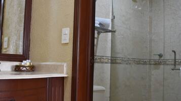 A bathroom with a wooden vanity, a toilet, and a glass-enclosed shower area.