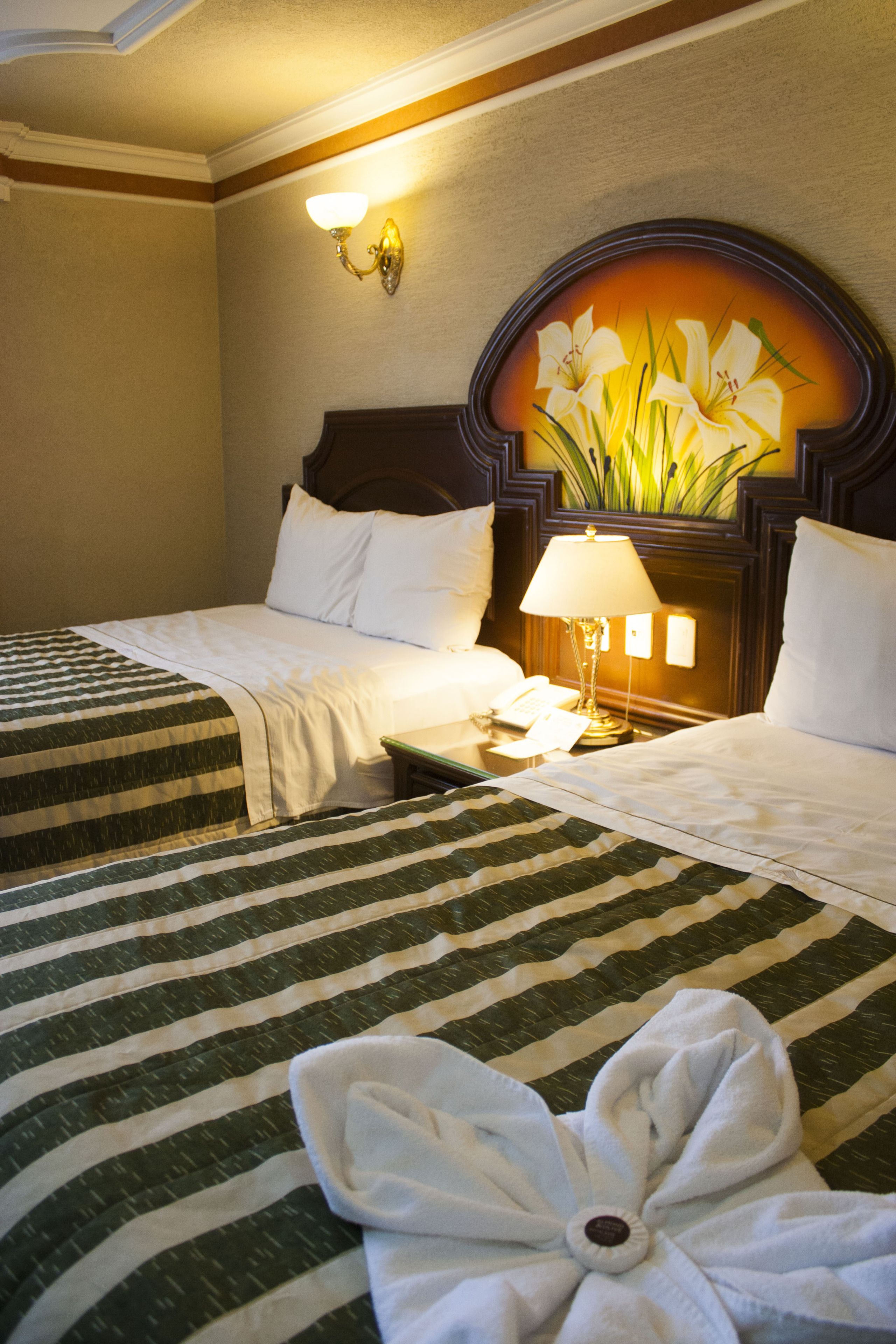Een hotelkamer met twee bedden, een nachtkastje met een lamp en een wandlamp.