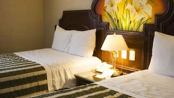 Een hotelkamer met twee bedden, een nachtkastje met een lamp en een wandlamp.