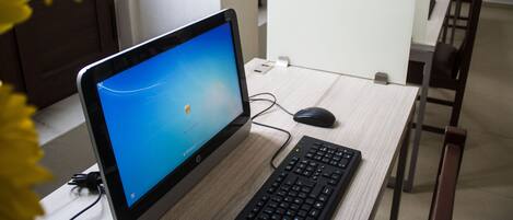 Ein Laptop auf einem Schreibtisch mit Tastatur, Maus und einer Blume im Vordergrund.
