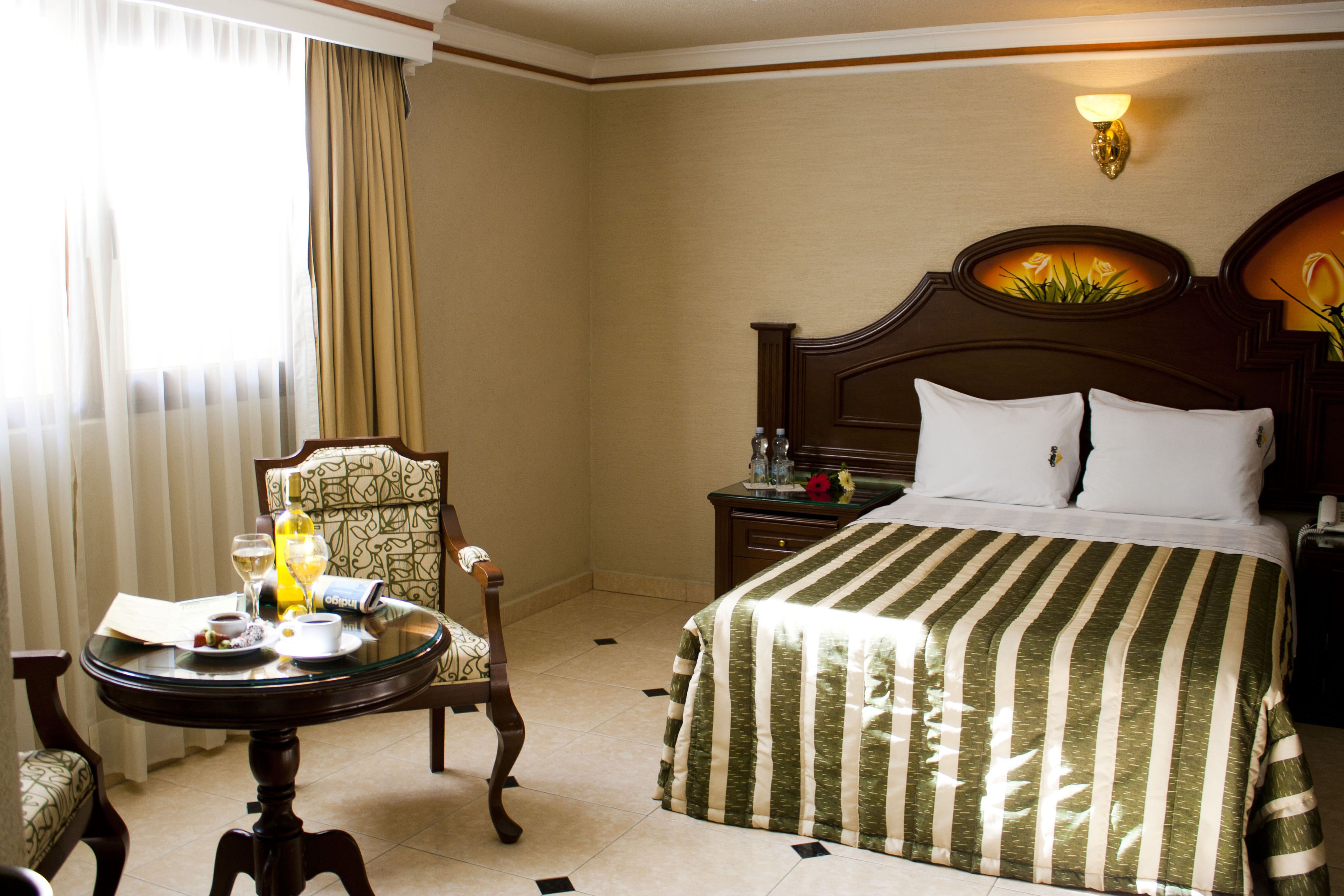 Une chambre d’hôtel comprenant un lit, une table de chevet, une chaise et une petite table avec des articles pour le petit-déjeuner.