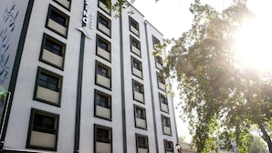 Un edificio de varios pisos con un llamativo letrero de "CASINO", grandes ventanales y vistas a árboles.