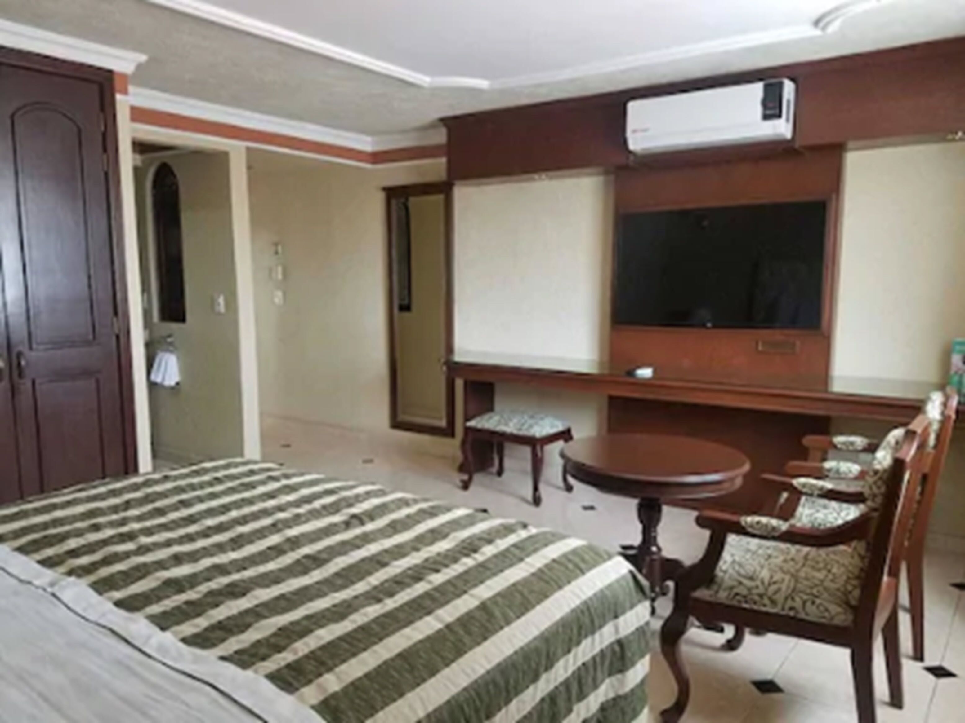 Ein Hotelzimmer mit Bett, Fernseher, kleinem Tisch und Stuhl.