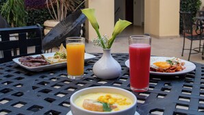 Una mesa con alimentos para el desayuno, incluyendo un tazón de sopa, un plato de huevos y dos bebidas.