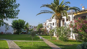A white building with balconies, surrounded by greenery and a clear sky. - Siesta Mar (Alayor)