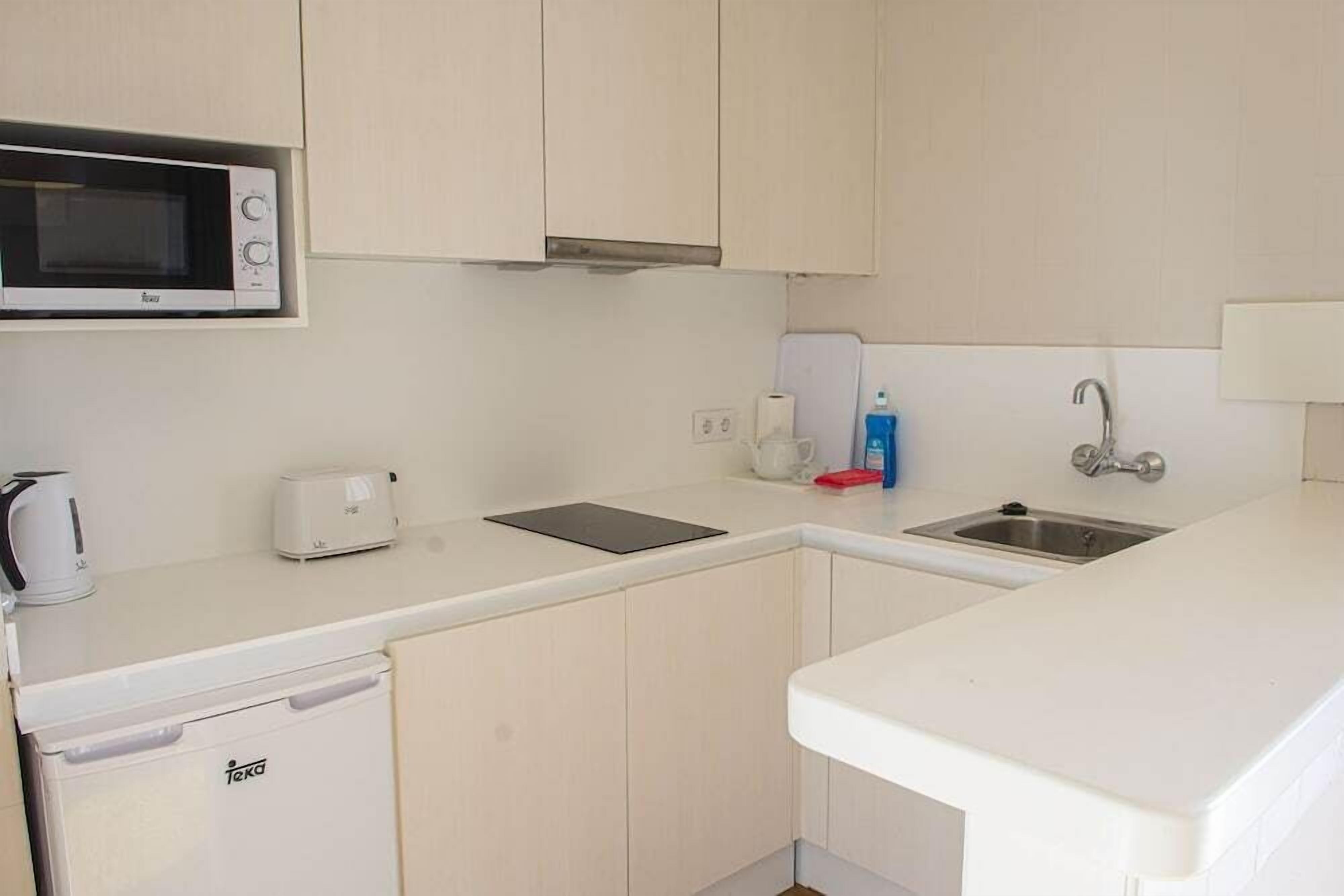 A compact kitchen with a microwave, toaster, and sink.