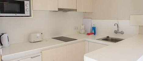 A compact kitchen with a microwave, toaster, and sink.