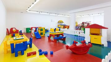 A brightly colored playroom with a yellow table, blue chairs, and various toys.