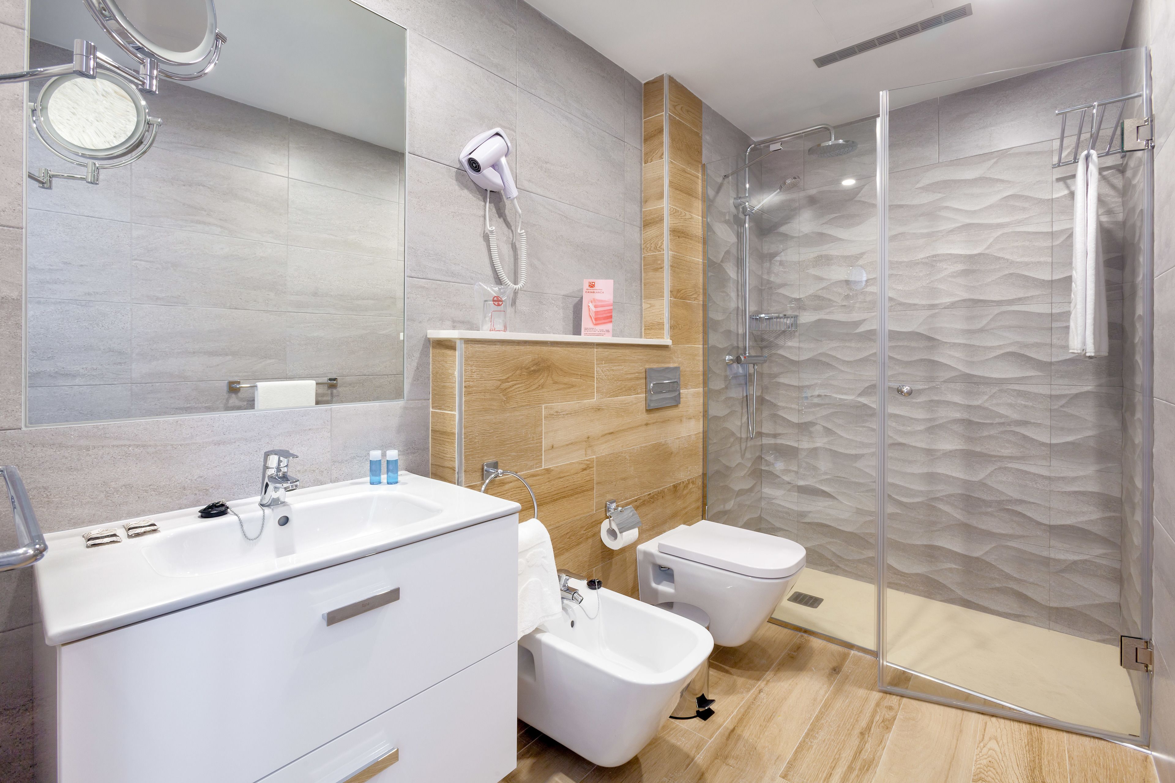 A modern bathroom with a large sink, bidet, and glass-enclosed shower.
