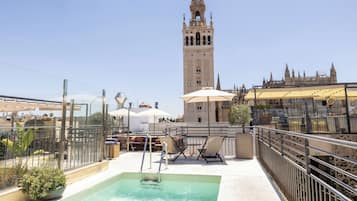 Relax on the rooftop terrace with a view of the historic tower, featuring a swimming pool and comfortable outdoor seating.