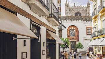 Una calle estrecha flanqueada por edificios, con una iglesia destacada y un gran arco, y gente caminando.
