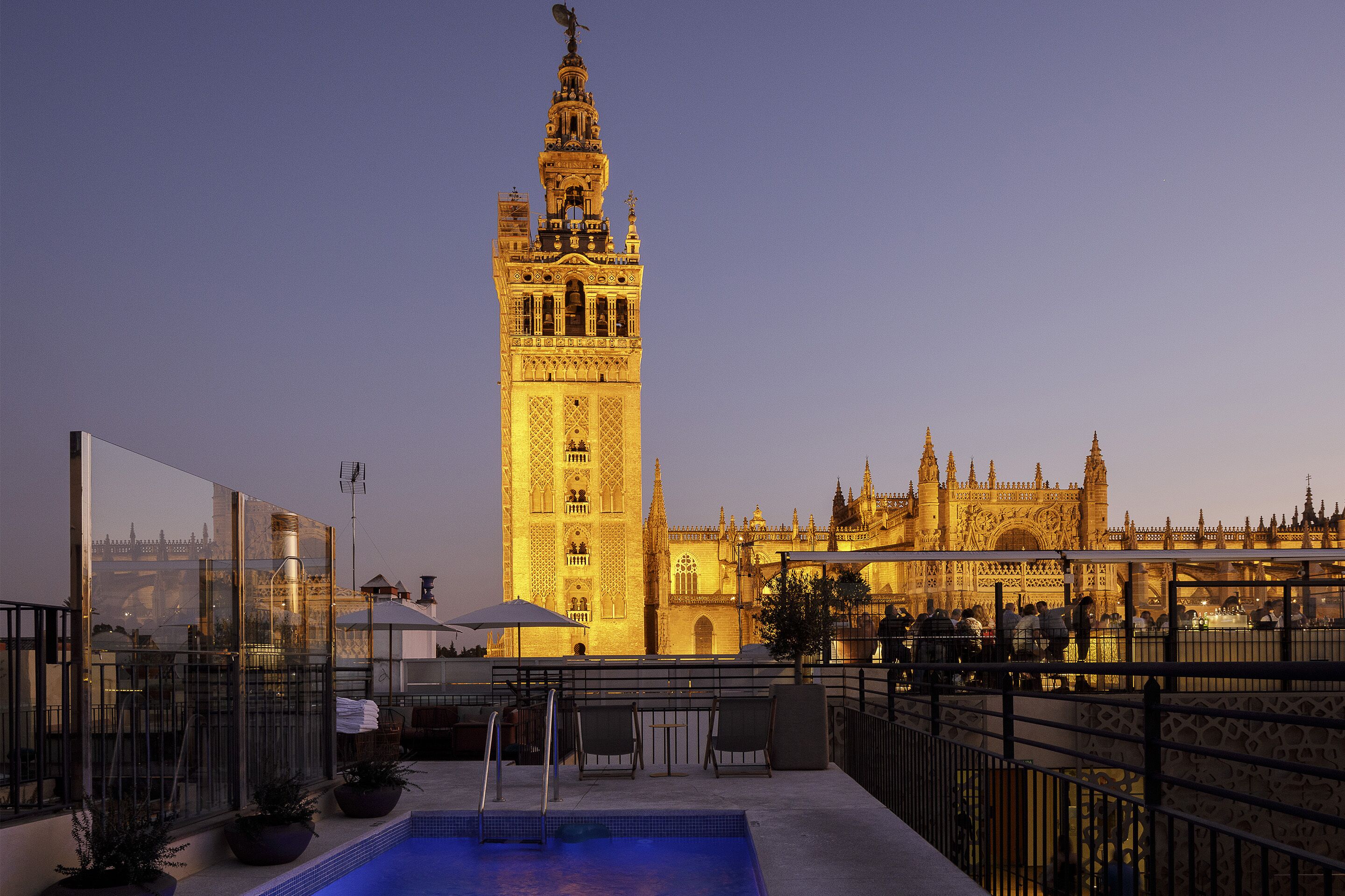 Zona de piscina en la azotea con vistas a un edificio histórico y una torre alta.