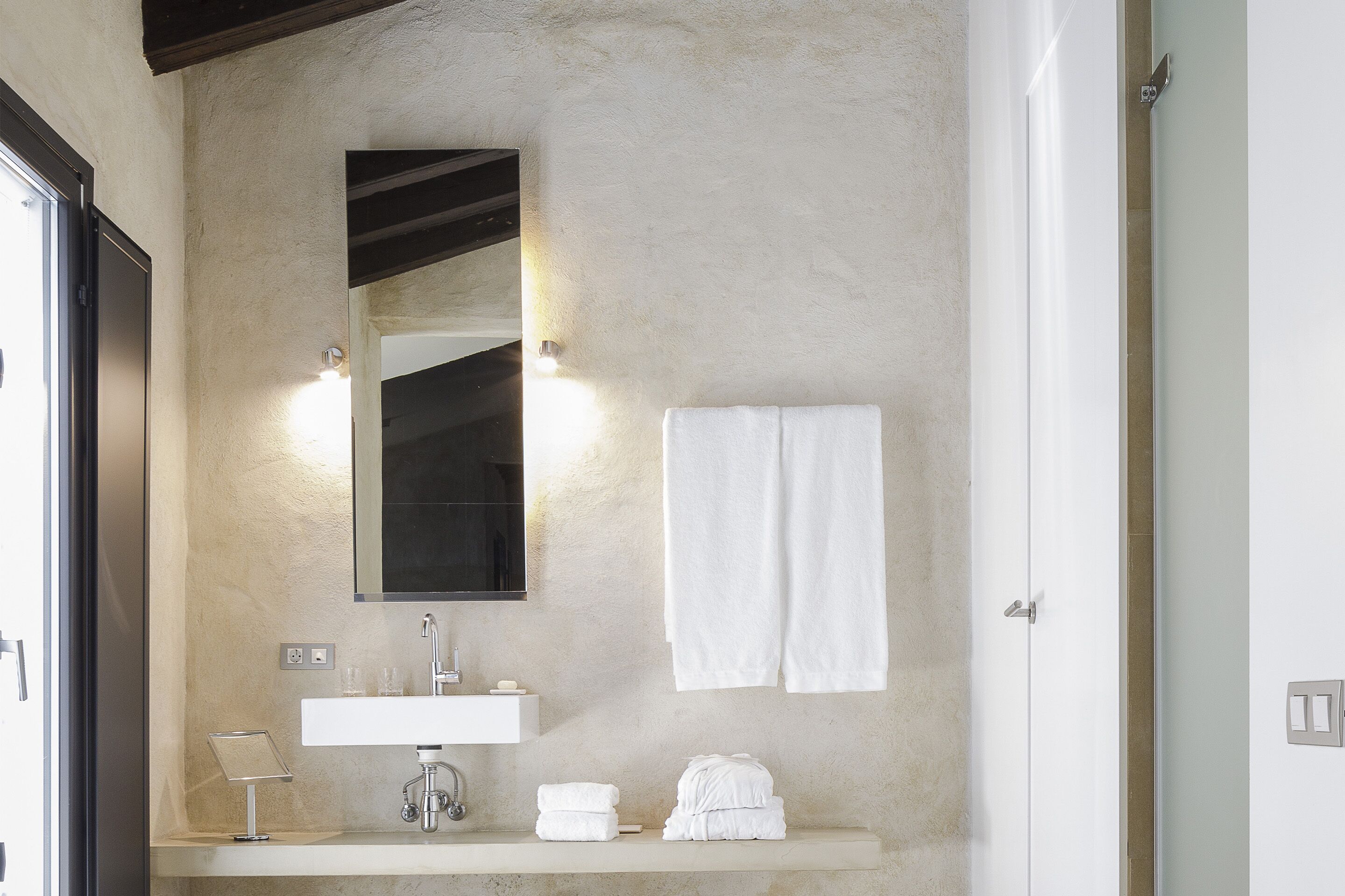 Un baño con un lavamanos blanco, un espejo y dos toallas sobre el mostrador.
