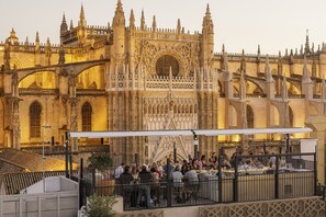 A historic building with intricate architecture, a covered outdoor seating area, and a view of the structure. - EME Catedral Mercer Hotel (Seville)