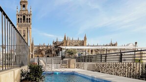 A rooftop pool with a view of a historic building with a tall tower. - EME Catedral Mercer Hotel (Seville)