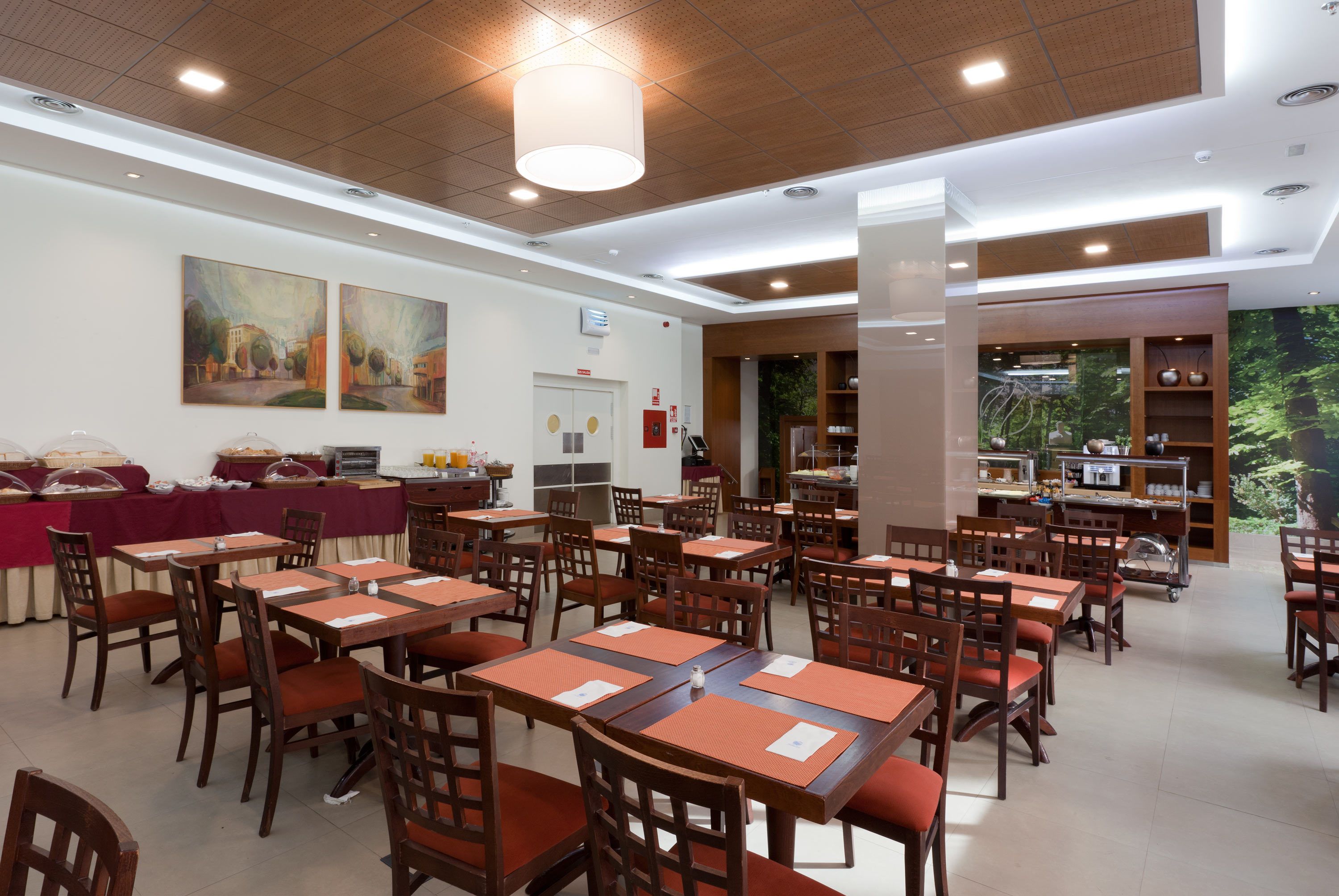 A dining area with multiple tables and chairs, a buffet setup, and a large painting on the wall.