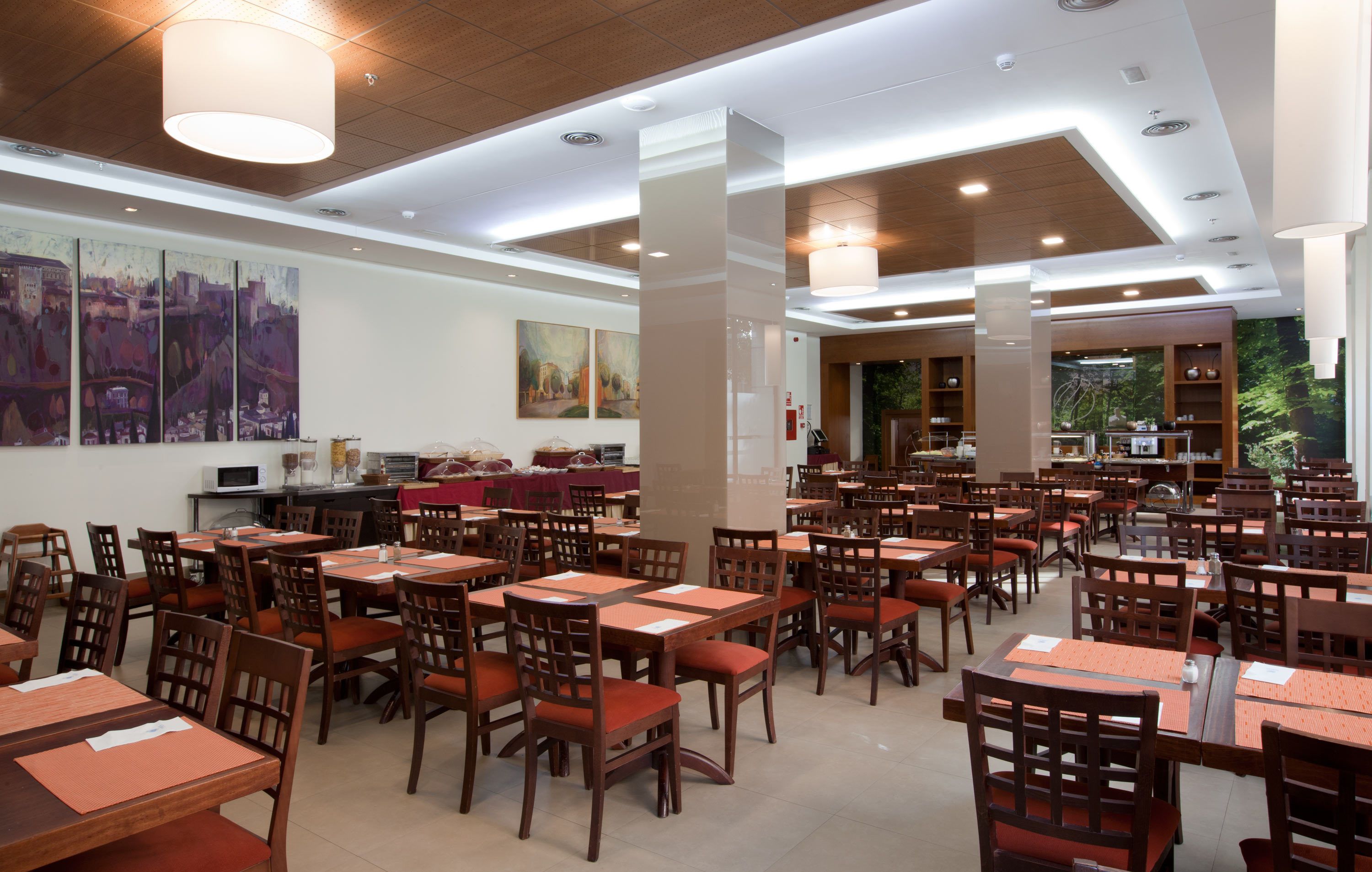 A spacious dining area with multiple tables and chairs, wooden ceiling, and artwork on the walls.