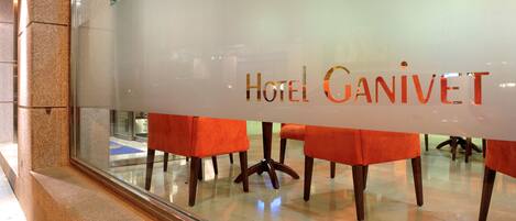 Interno di un hotel con una parete di vetro che mostra il nome "HOTEL GANIVET".