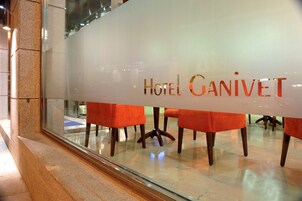 Ein Hotelinterior mit einer Glaswand, auf der der Name "HOTEL GANIVET" zu sehen ist.