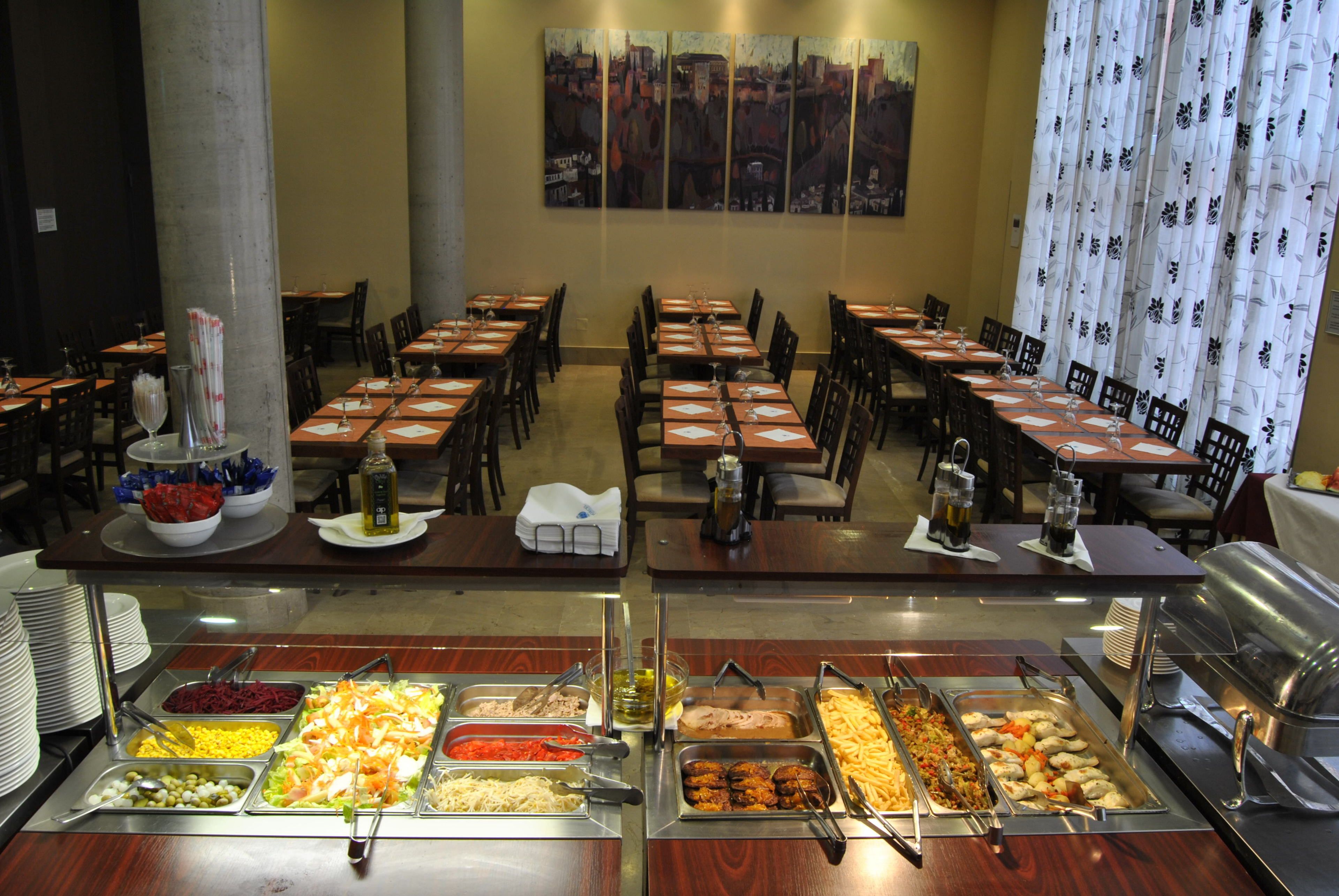 A buffet setup with various food items and a seating area with tables and chairs.